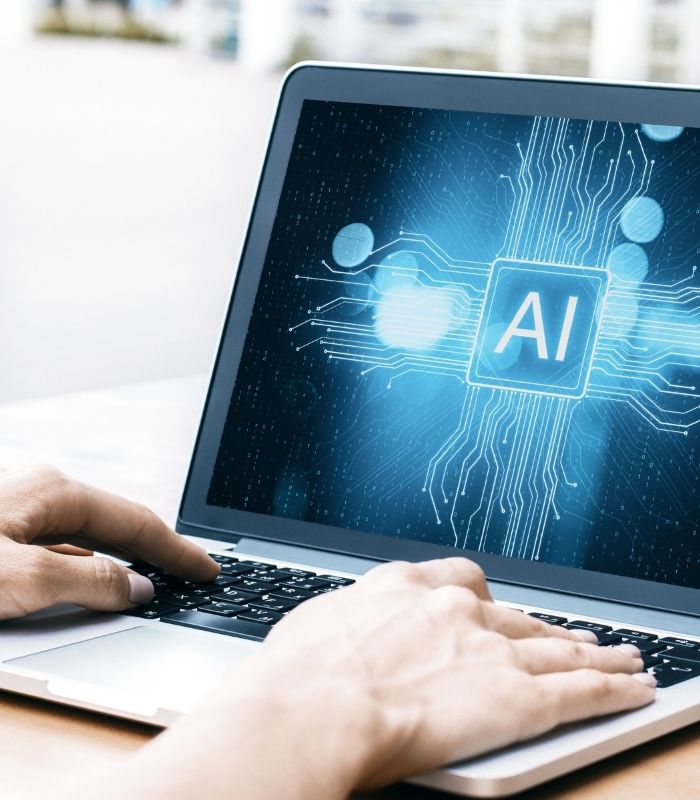 Hände liegen auf Laptoptastatur, der Bildschirm zeigt eine KI-Chip-Grafik und digitale Schaltkreisen